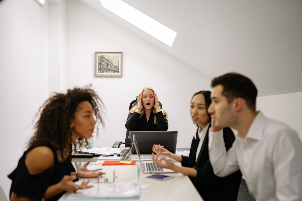 Why DEI roles are disappearing illustrated through a stressed woman excluded from a team meeting.
